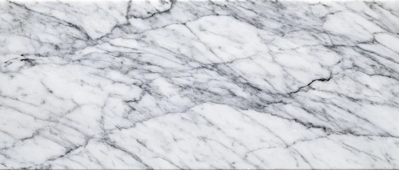 Close-up of white carrara marble surface with natural gray veining filling the frame