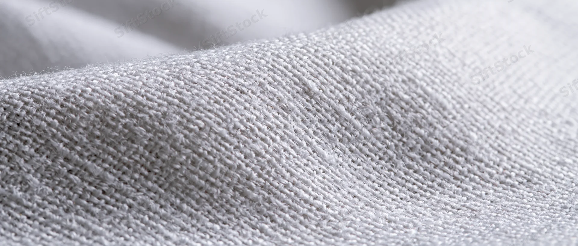 Close-up of white woven linen fabric showing detailed texture and natural weave pattern