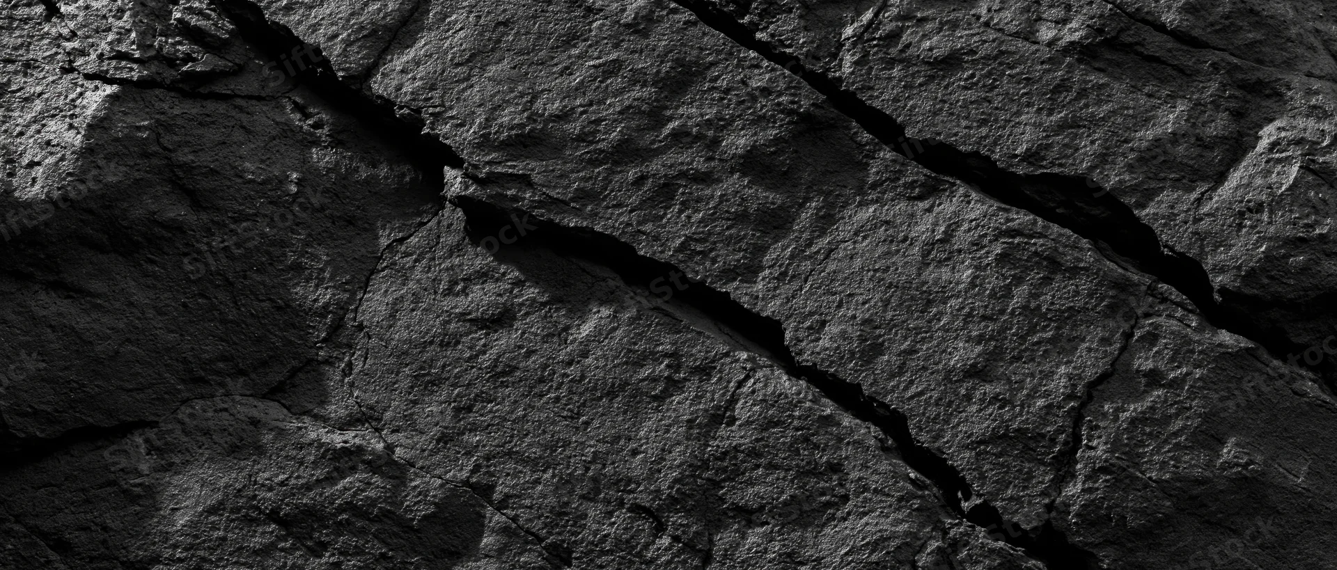 Close-up of a cracked dark basalt rock face showing natural fractures and rough texture