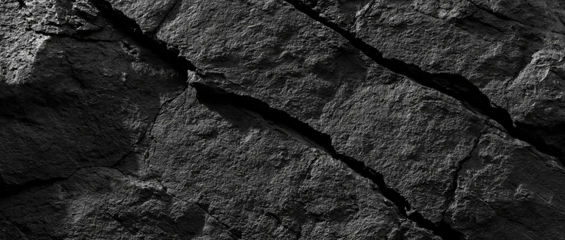 Close-up of a cracked dark basalt rock face showing natural fractures and rough texture