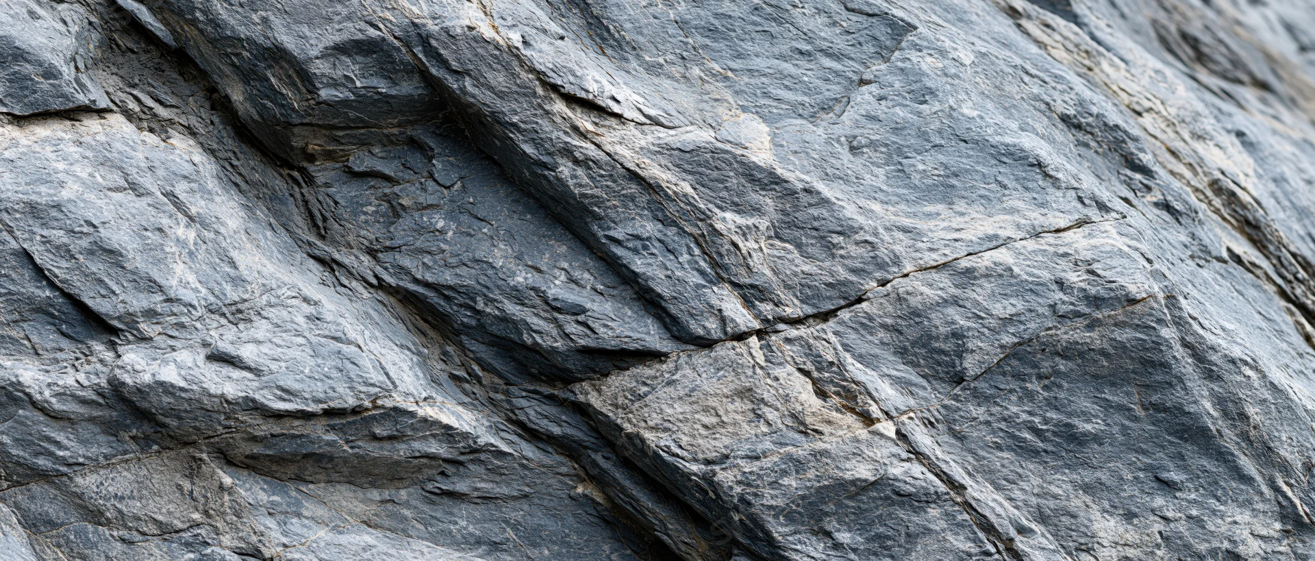 Close-up of a rough natural rock face with visible layers and cracks