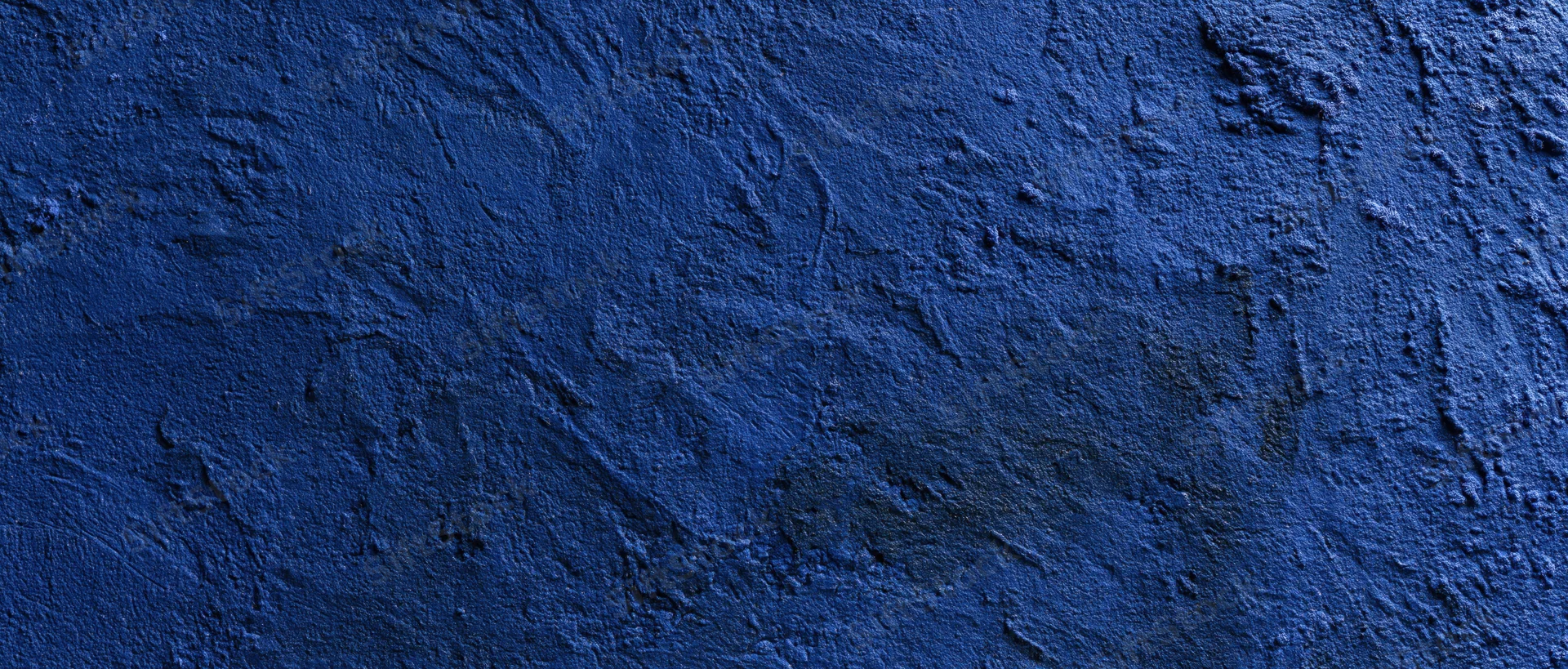 Close-up of a rough blue-painted concrete wall with textured plaster finish