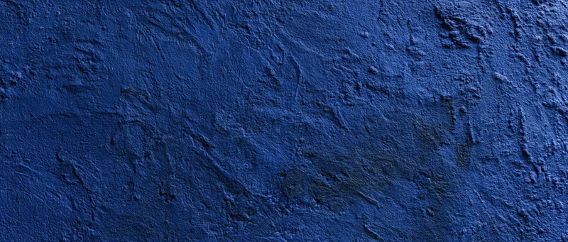Close-up of a rough blue-painted concrete wall with textured plaster finish