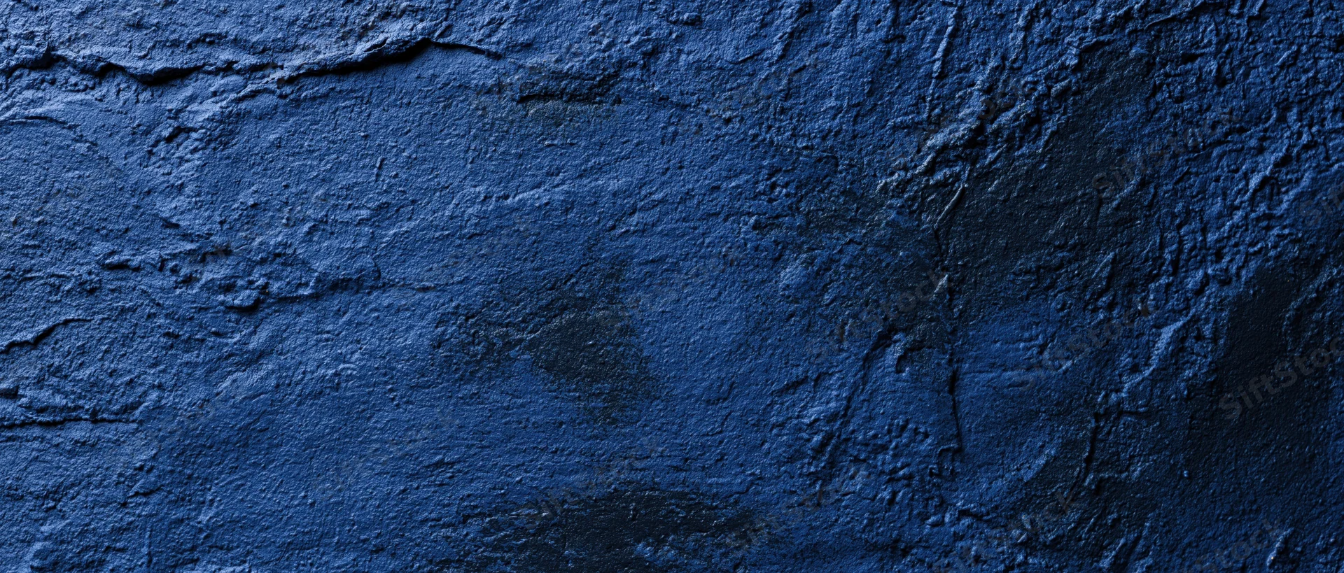 Close-up of a rough blue-painted concrete wall with visible cracks and texture