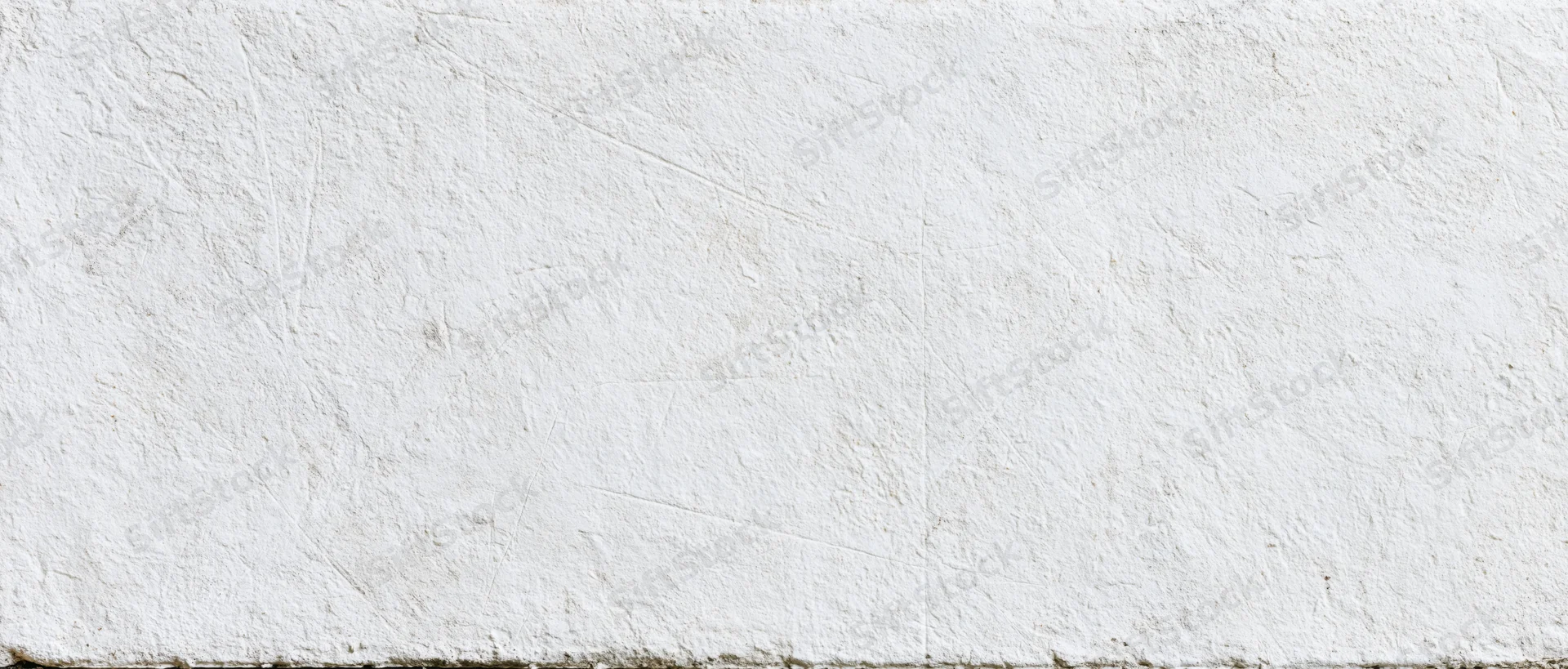Close-up of a weathered white concrete wall surface with visible texture and cracks