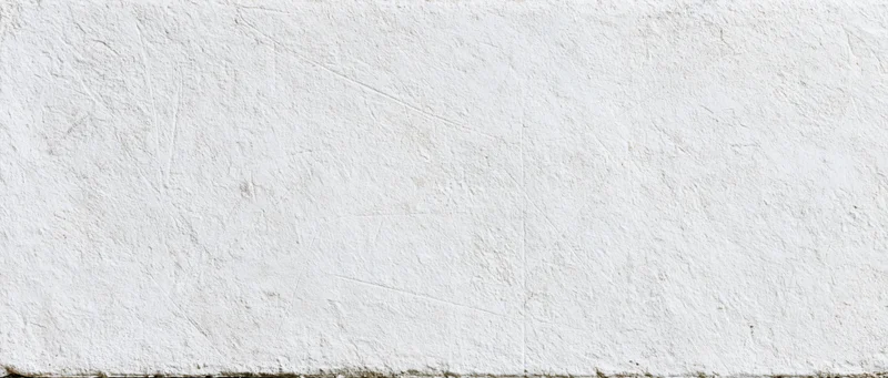 Close-up of a weathered white concrete wall surface with visible texture and cracks