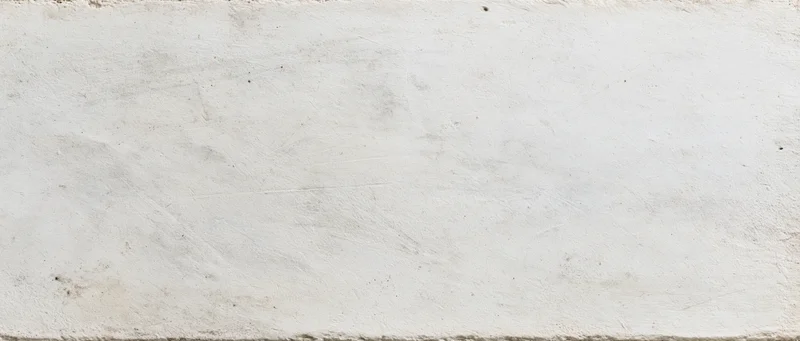 Weathered white concrete wall surface with rough texture and subtle discoloration