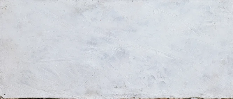 Weathered white concrete wall surface with visible texture and cracks
