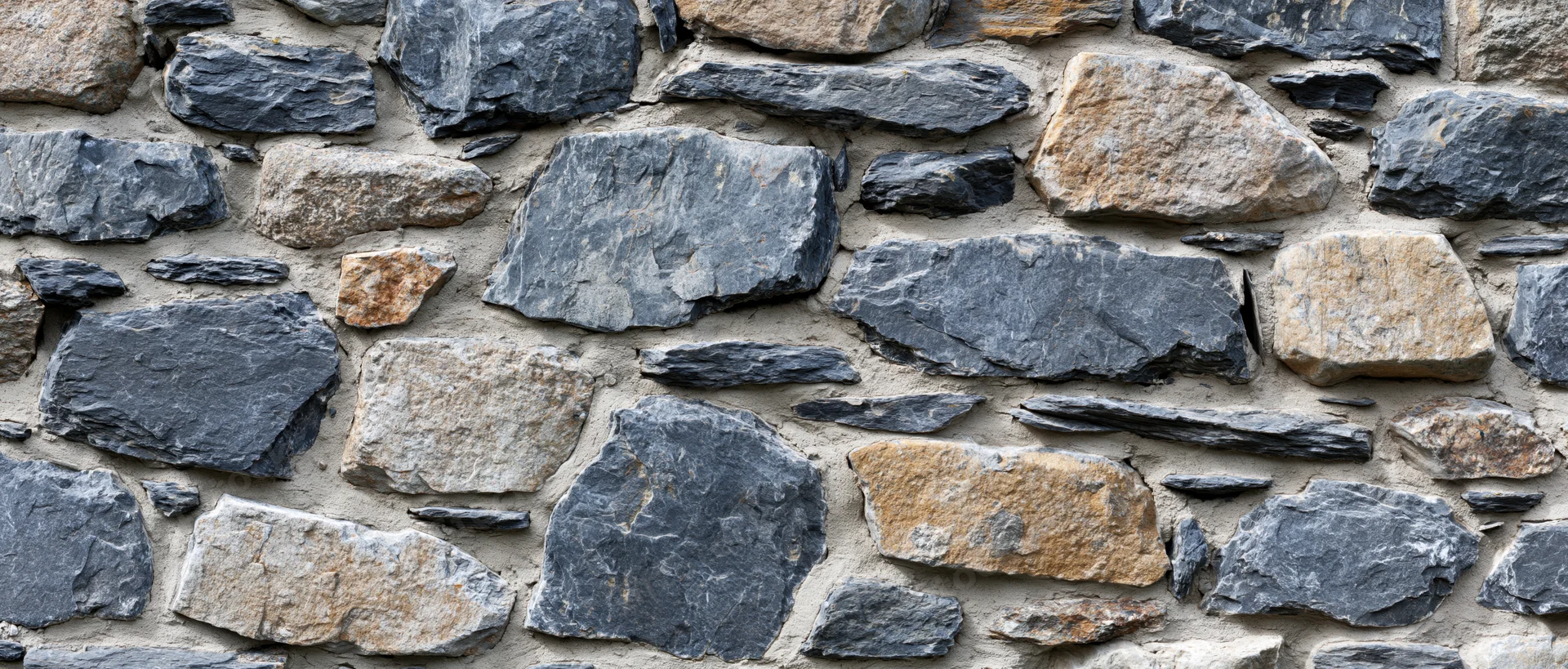 Close-up of an old dry-stone rubble wall with irregularly shaped stones and mortar joints