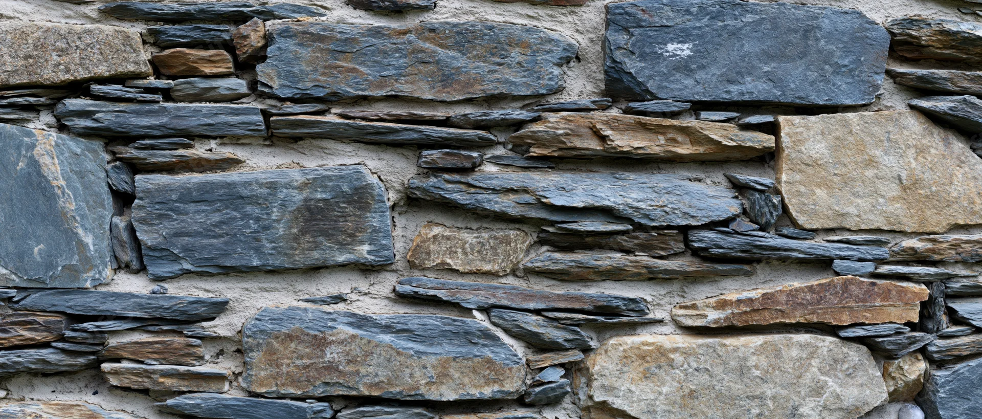 Close-up of an old dry-stone rubble wall with irregularly shaped stones and natural weathering