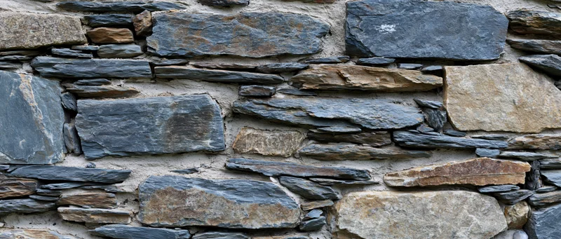 Close-up of an old dry-stone rubble wall with irregularly shaped stones and natural weathering