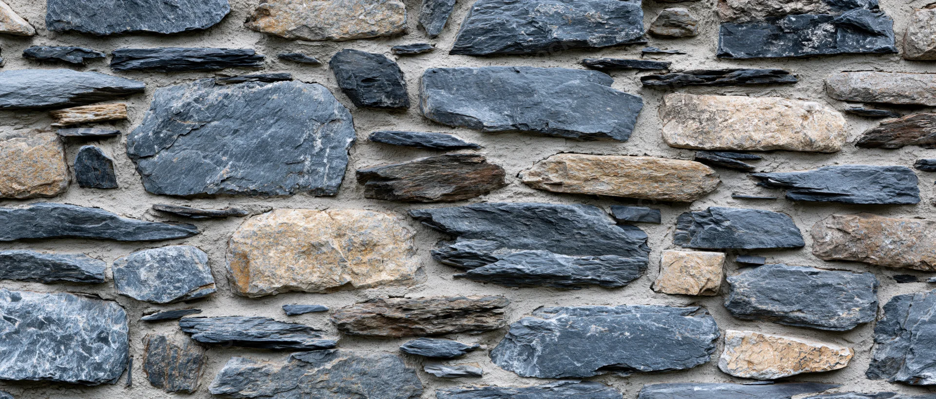 Close-up of an old dry-stone rubble wall with irregularly shaped stones and natural textures