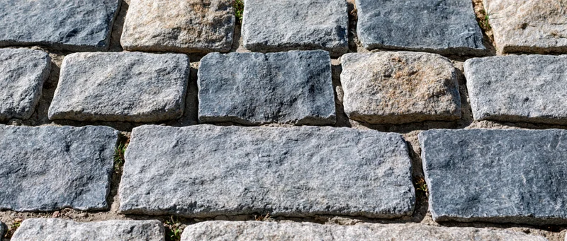 Close-up of old granite cobblestones arranged in a paved surface outdoors