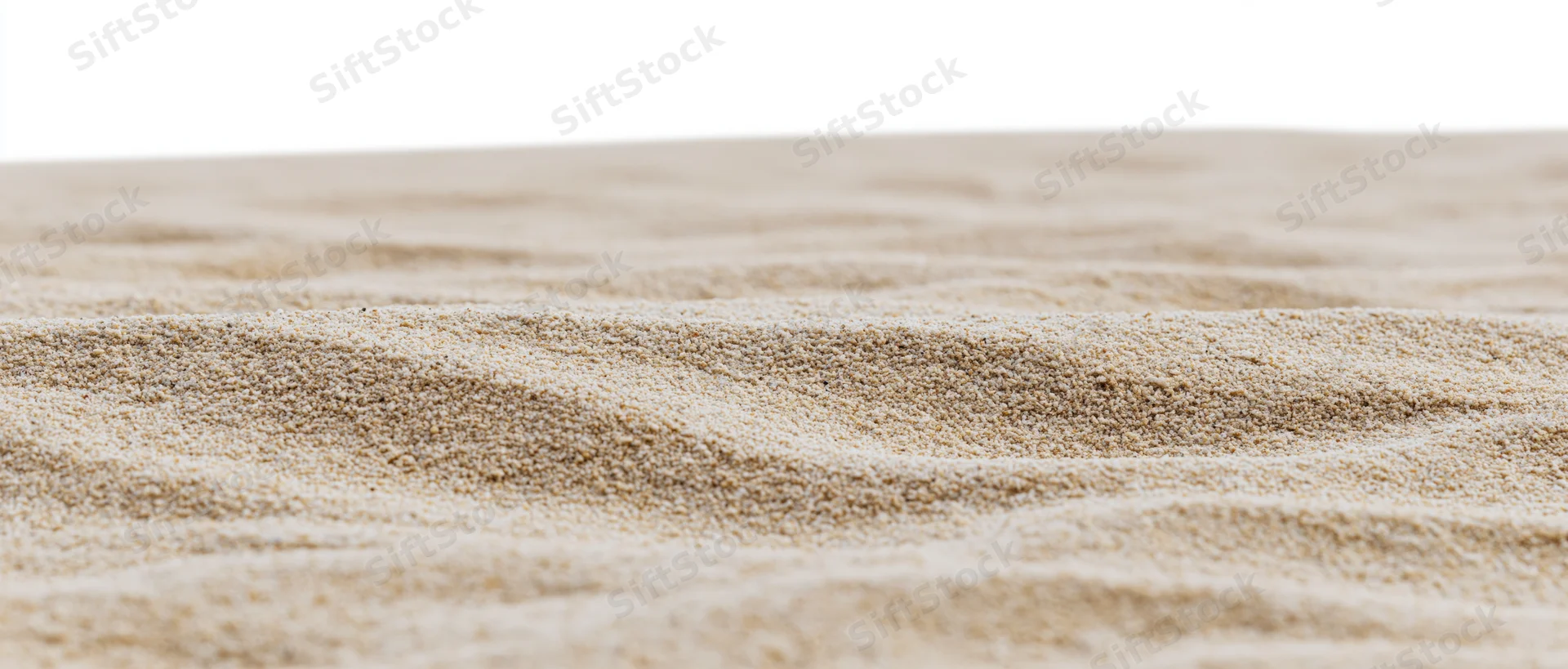 Closeup of dry beach sand with wind-formed ripples on a white background