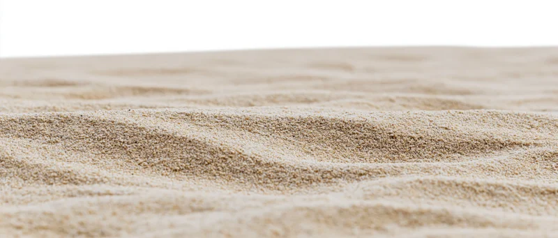 Closeup of dry beach sand with wind-formed ripples on a white background