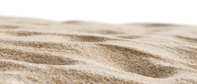 Close-up of dry beach sand with wind-formed ripples on a white background