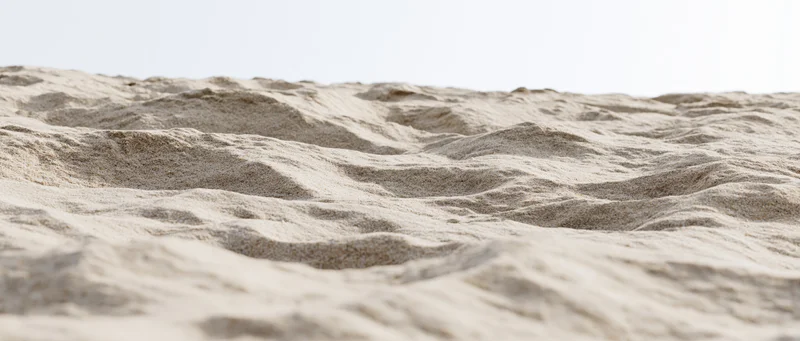 Closeup of dry beach sand with wind-formed ripples at ground level