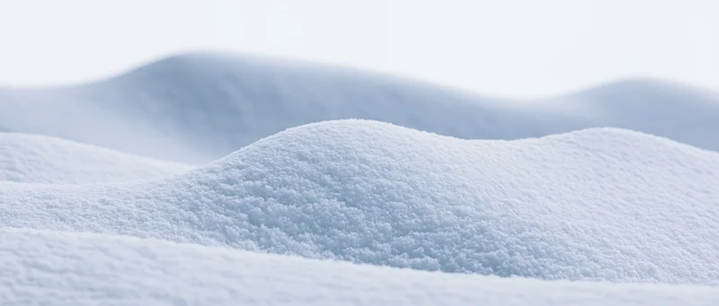 Close-up of soft snow drifts undulating across a snowy landscape