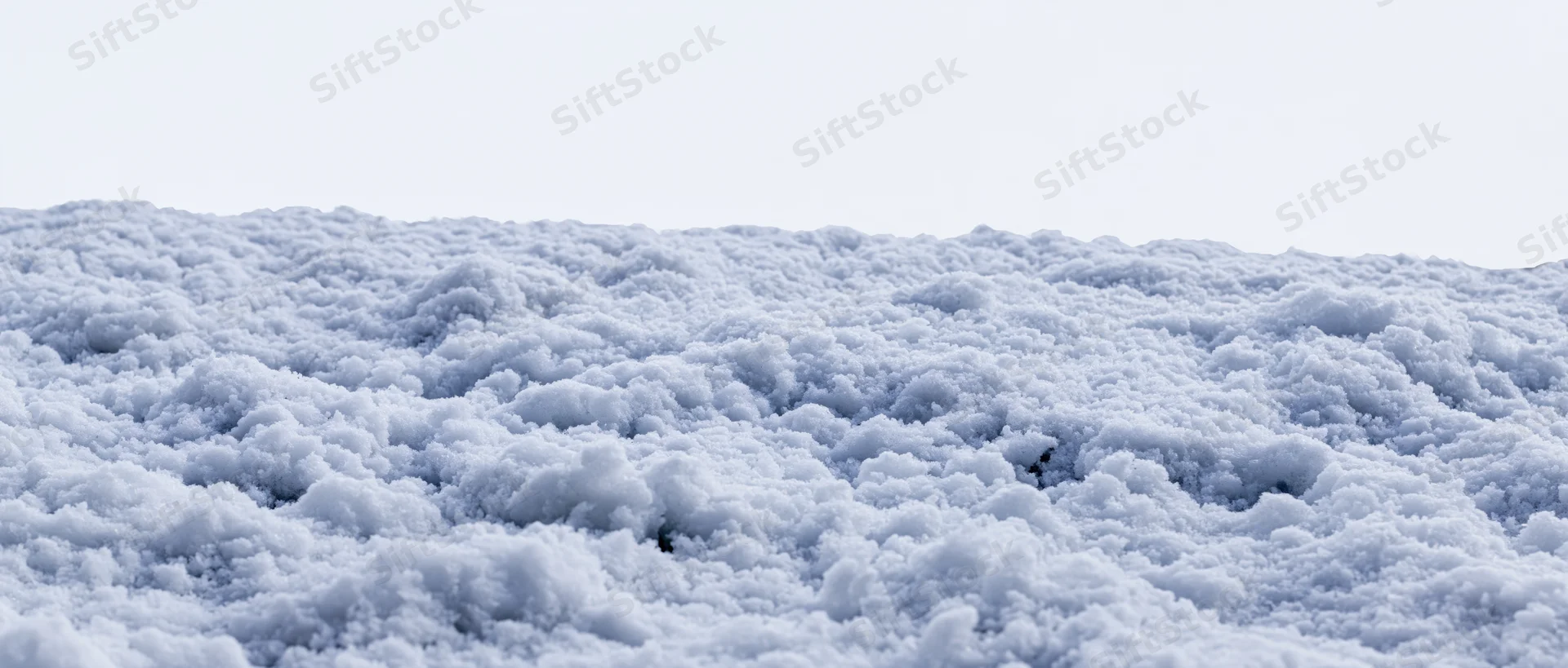 Close-up of disturbed snow surface at ground level under overcast sky