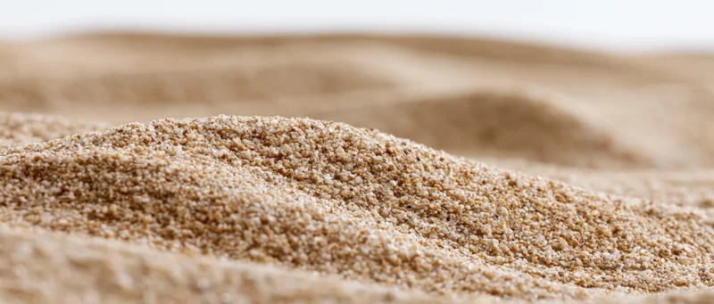 Close-up low-angle view of dry sand ripples stretching across a flat surface