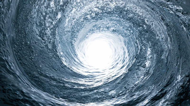 Swirling water forming a vortex with light at the center, viewed from inside the spiral