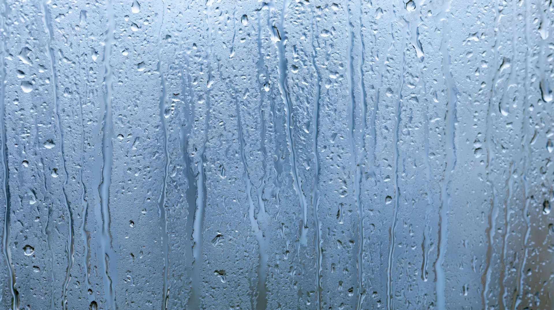 Raindrops and streaks on a glass window surface