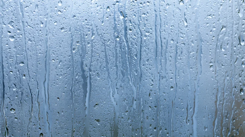 Raindrops and streaks on a glass window surface