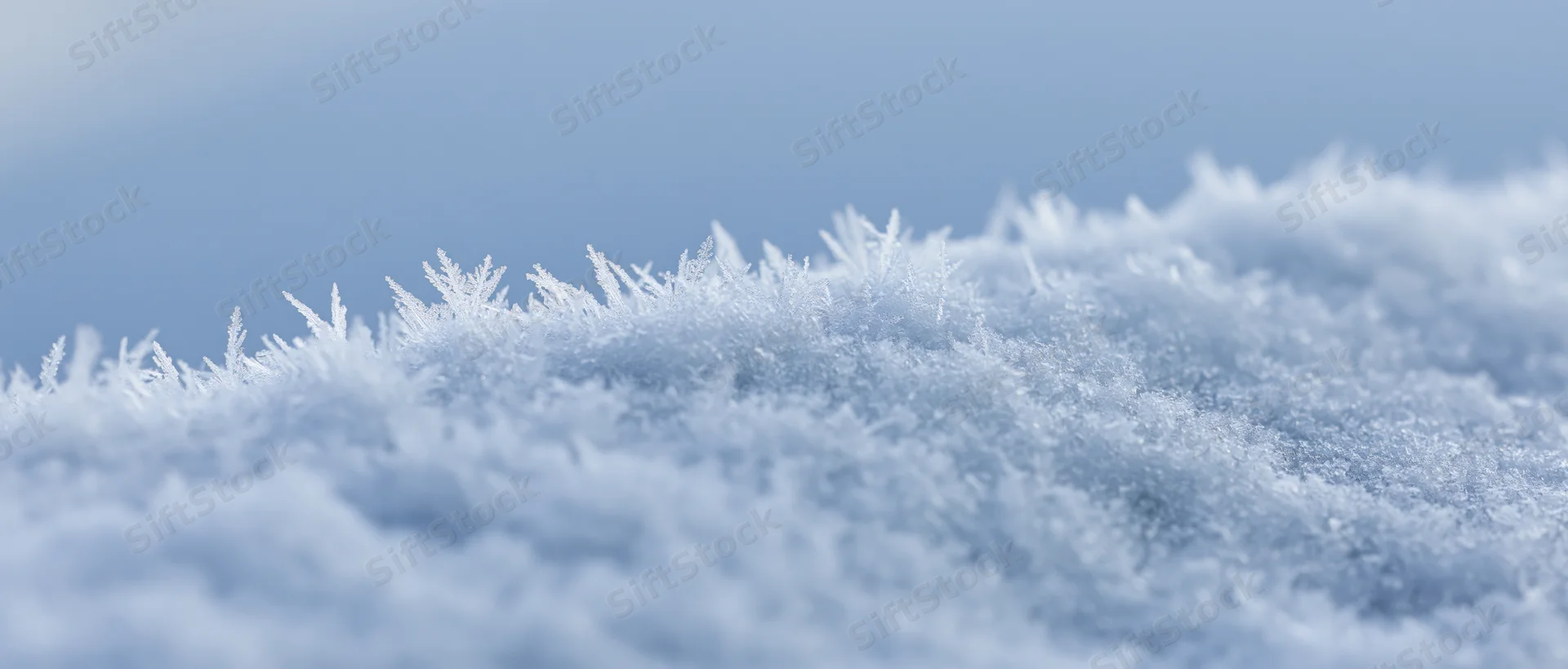 Closeup of frosty snow edge with crystalline ice formations under soft winter light