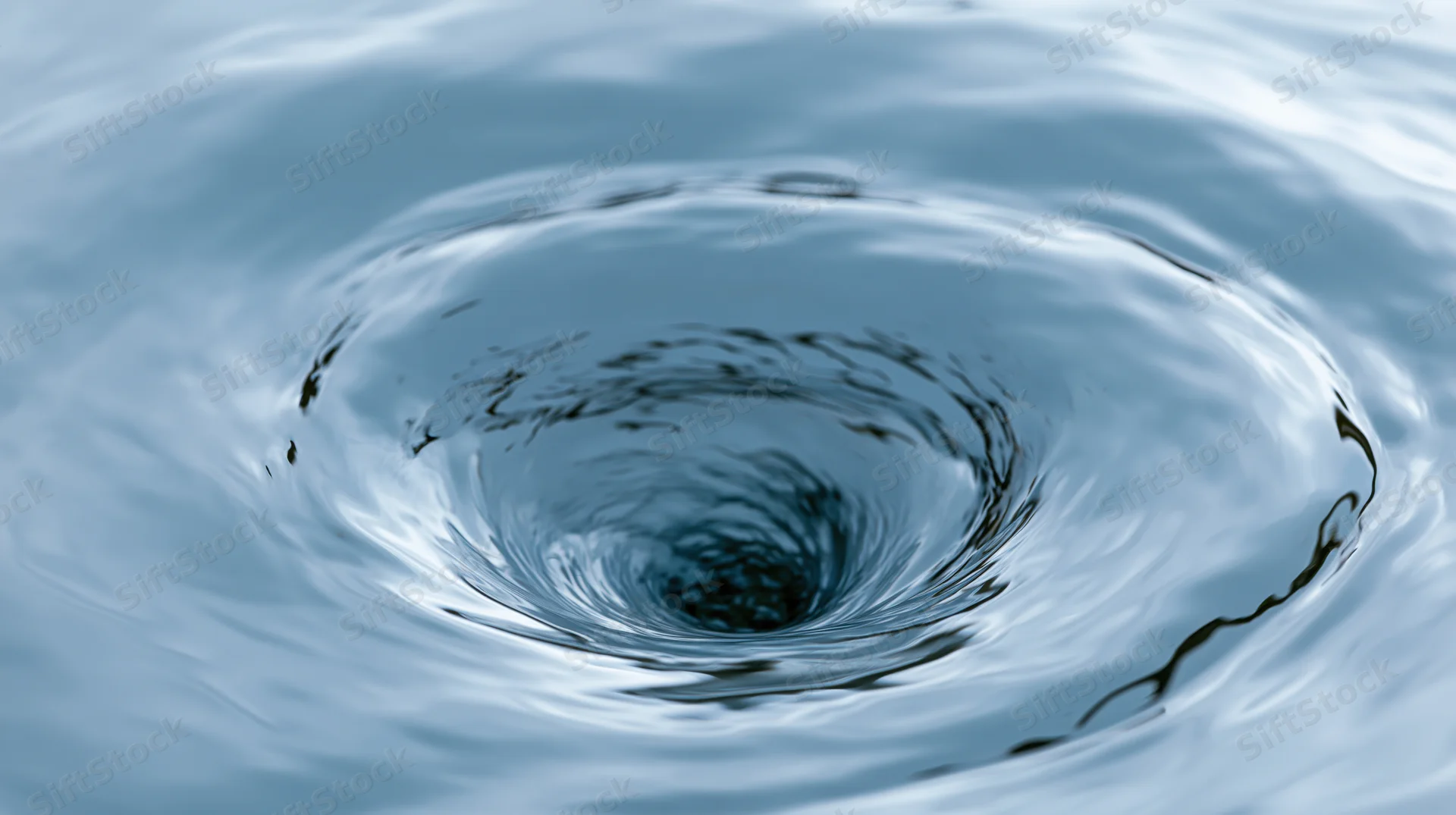 Close-up of a spinning water vortex forming concentric ripples on a calm surface