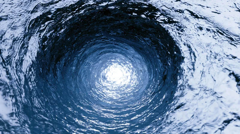 Swirling blue water forming a vortex with light reflecting on the surface