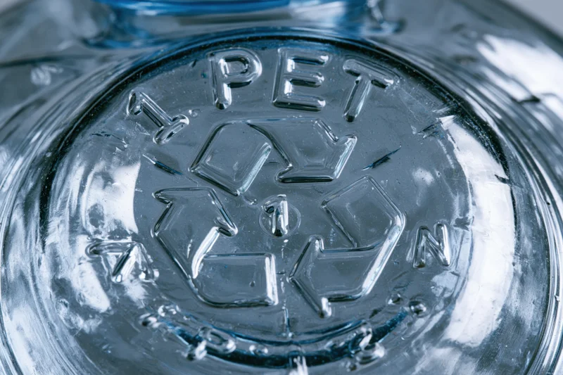 Close-up of the bottom of a clear plastic bottle showing the PET recycling symbol and resin code number 1