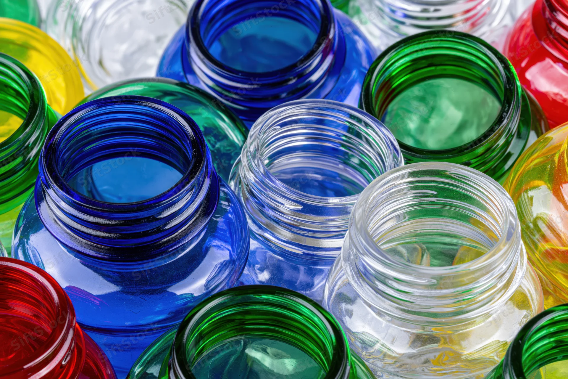 Close-up of scattered empty glass bottles in various colors viewed from above