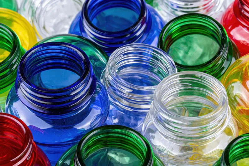 Close-up of scattered empty glass bottles in various colors viewed from above