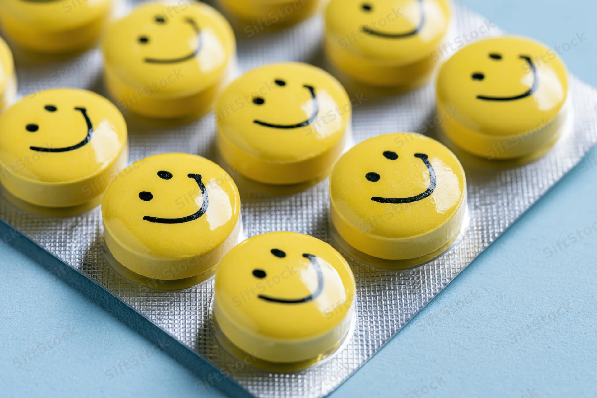 Yellow smiley-faced pills arranged in a blister pack on a blue surface