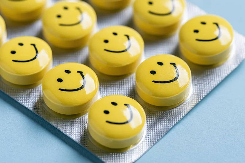 Yellow smiley-faced pills arranged in a blister pack on a blue surface