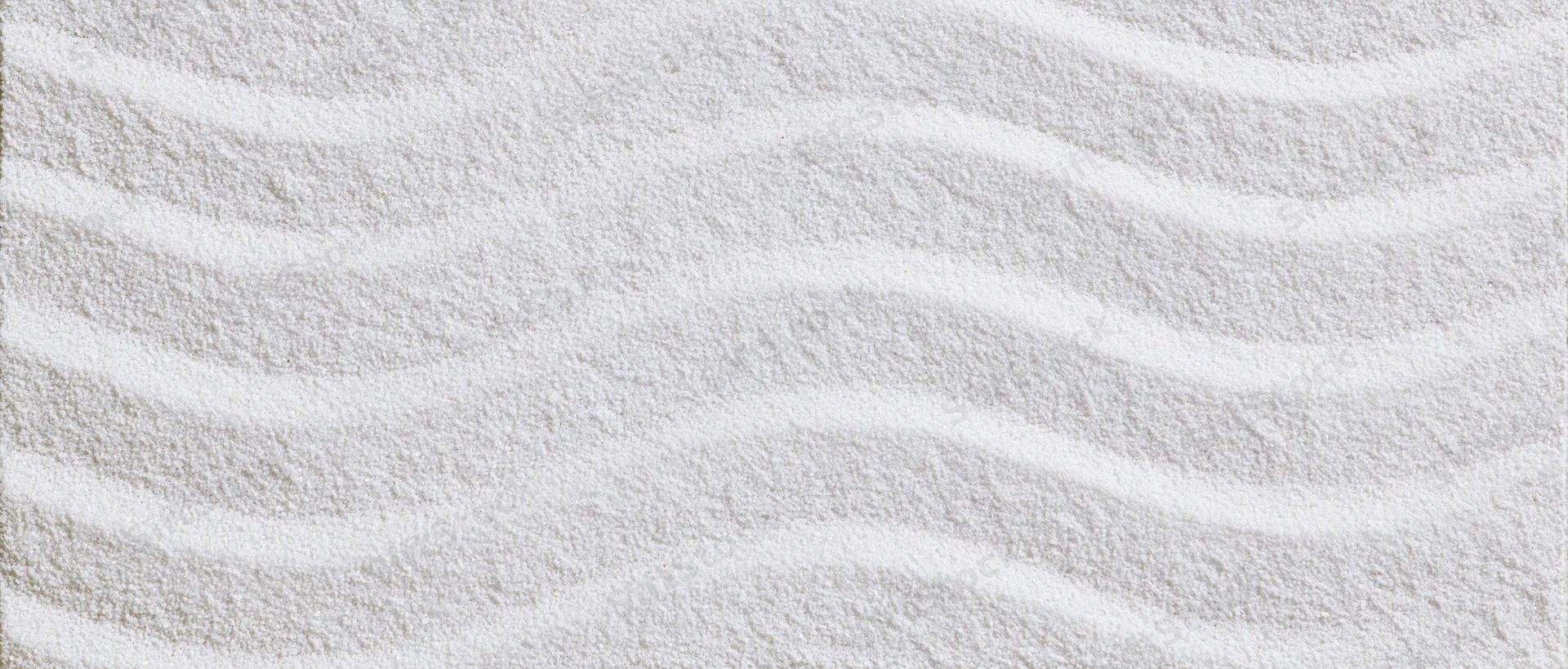 Raked white sand forming wavy patterns in a Japanese garden