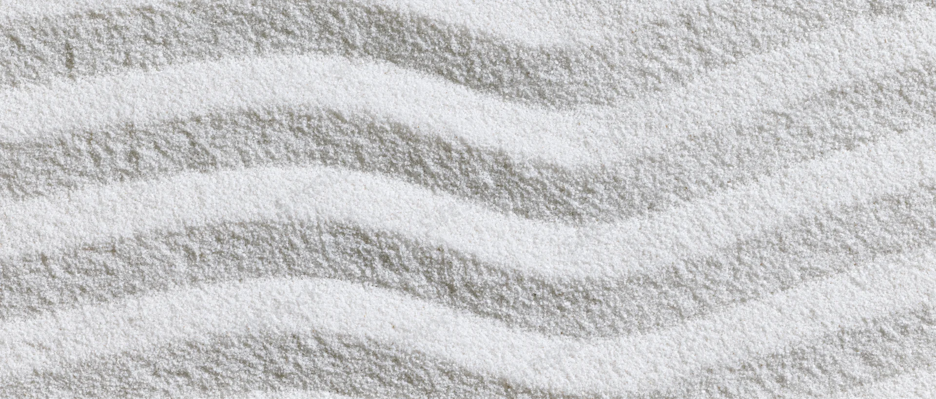 Raked white sand forming wavy patterns in a japanese garden