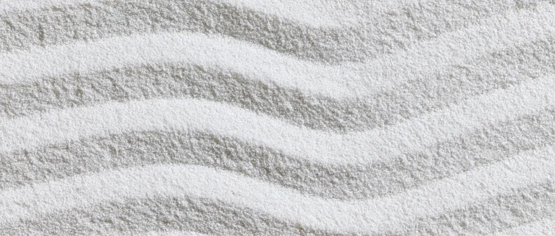 Raked white sand forming wavy patterns in a japanese garden