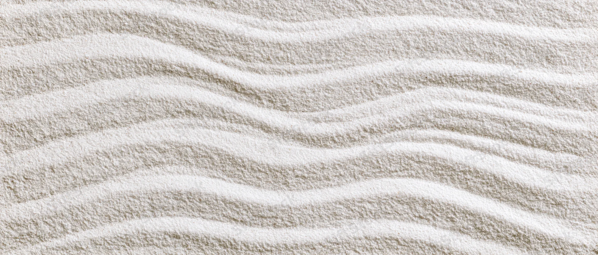 Raked white sand forming wavy lines in a Japanese garden