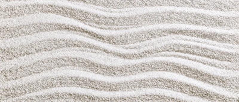 Raked white sand forming wavy lines in a Japanese garden