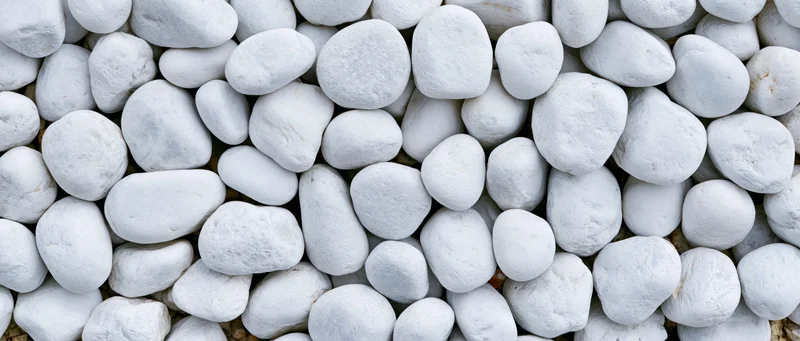 Close-up overhead view of smooth white pebbles densely spread on a flat surface
