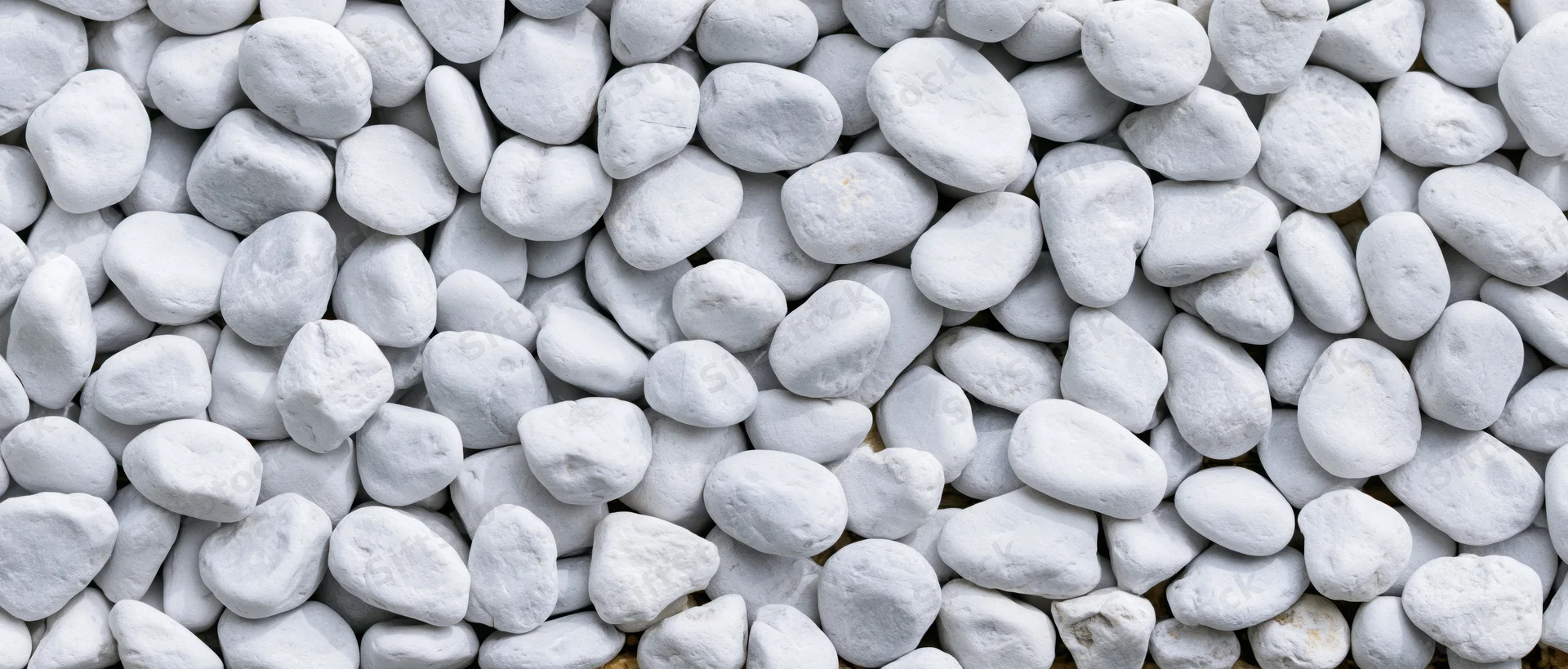 Close-up overhead view of smooth white pebbles densely spread across a flat surface