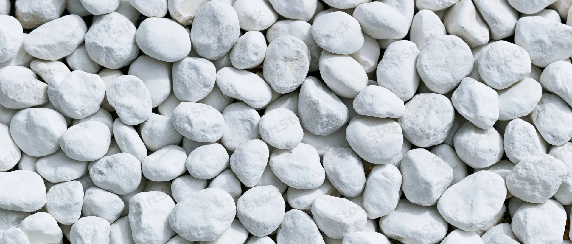 Closeup overhead view of smooth white pebbles densely spread as groundcover