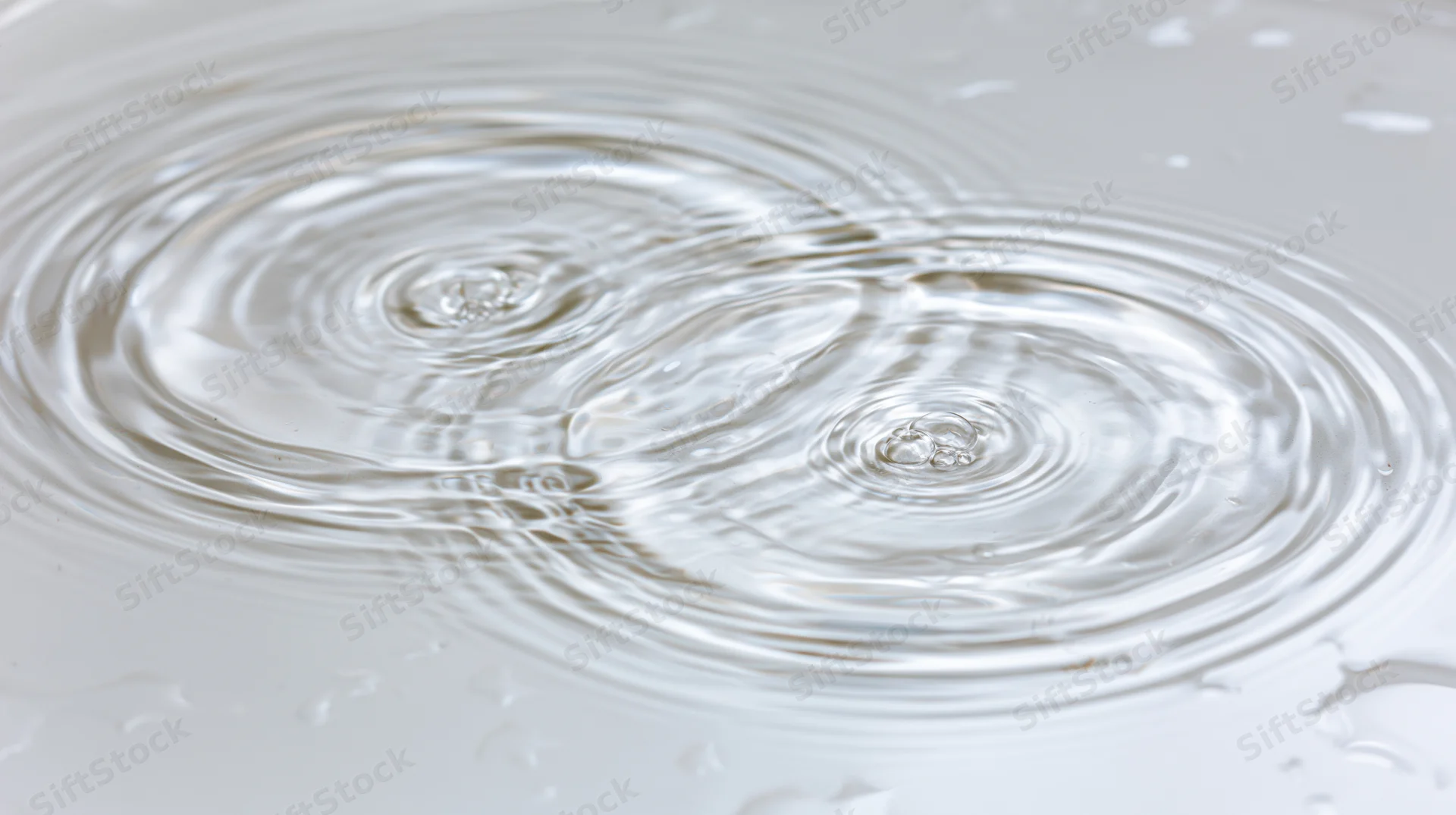 Close-up overhead view of ripples spreading on a shallow clear water surface