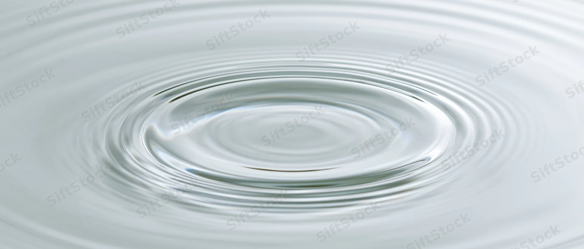Concentric ripples spreading across a calm water surface from a central droplet impact