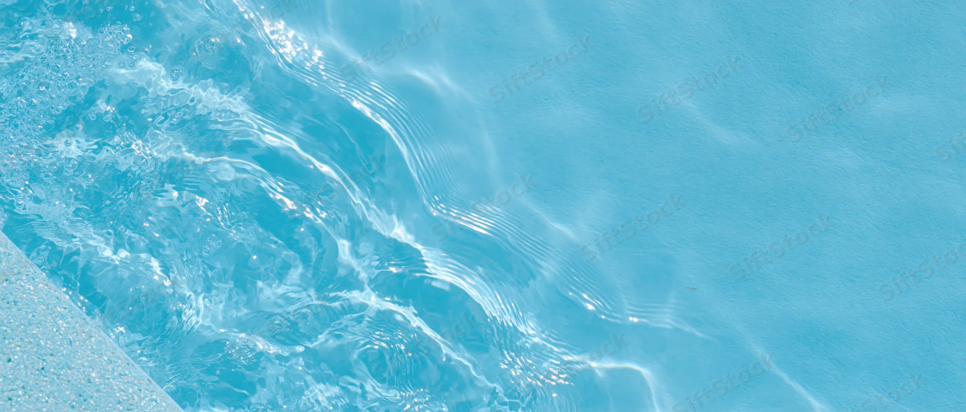 Overhead closeup of clear blue water with ripples and light reflections in a swimming pool