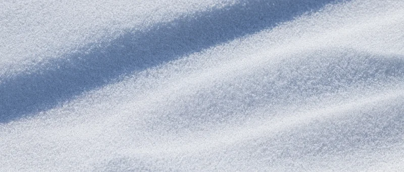 Close-up overhead view of smooth white beach sand with shallow ripples and soft shadows
