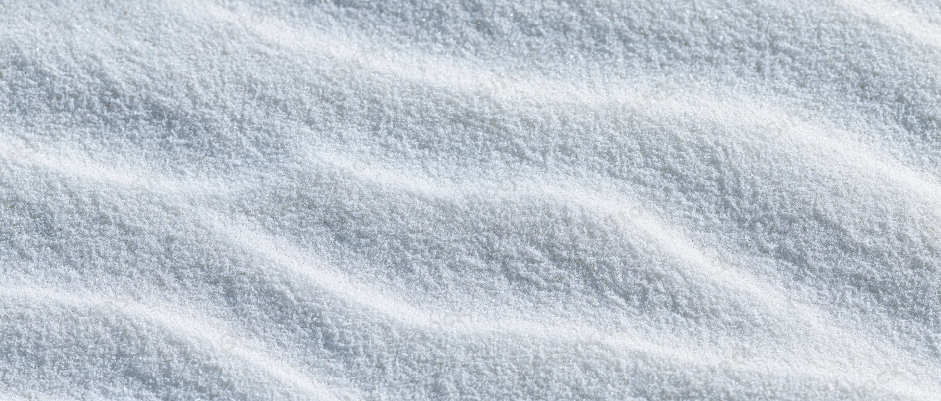 Close-up overhead view of smooth white beach sand with shallow ripples and natural texture