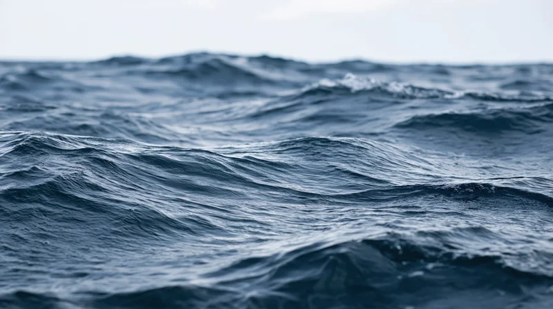 Close-up of deep ocean waves undulating at surface level under overcast sky