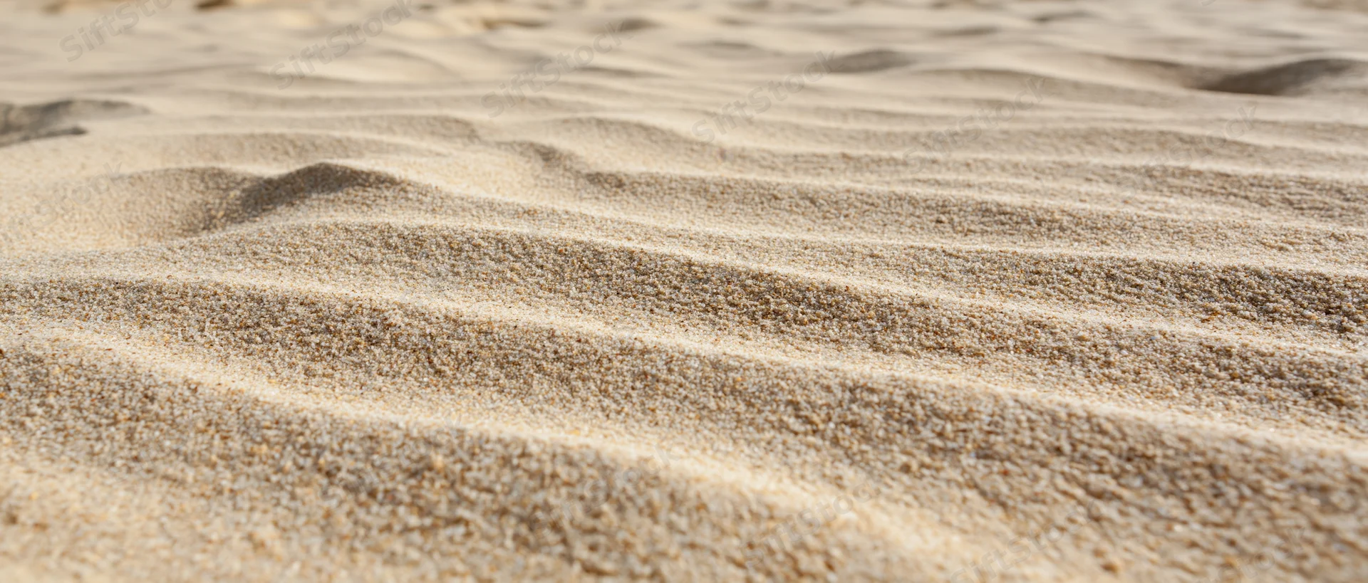 Close-up of rippled dry beach sand under sunlight